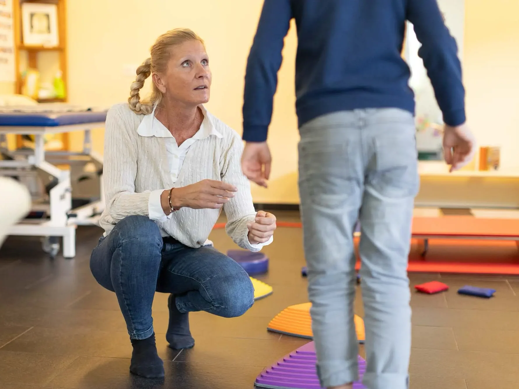 Therapeutin beobachtet Kind beim laufen über Balancesteine